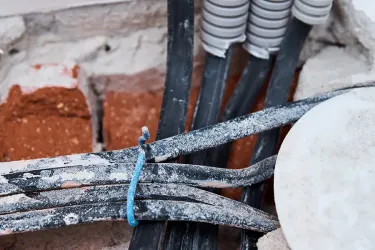 Dangerous water damaged wiring coming out of a brickwall