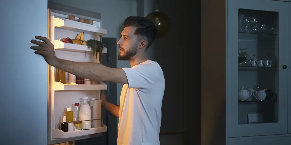 Sideview of a man looking into a refridgerator