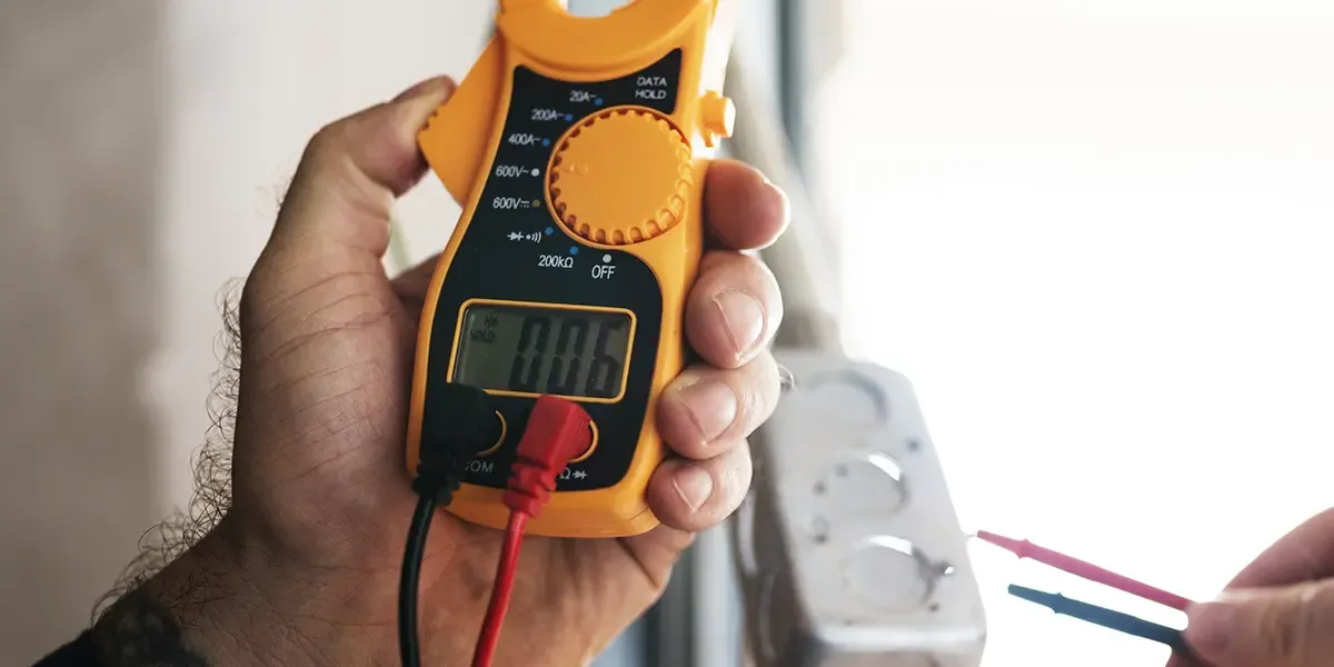 Electrician uses a voltage meter to check outlet voltage