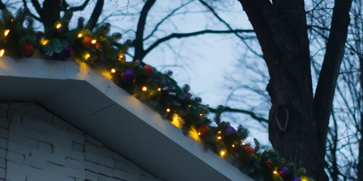 close up Christmas lighting and garland decorating the outside of a home