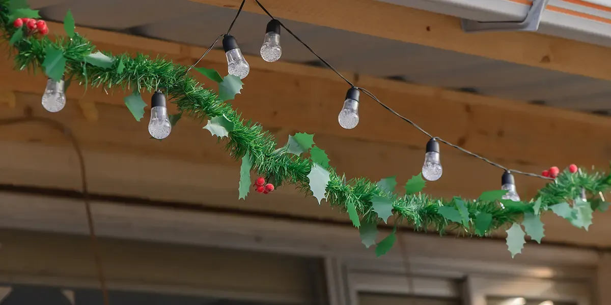 Christmas lights hang loosely from an overhand on a house