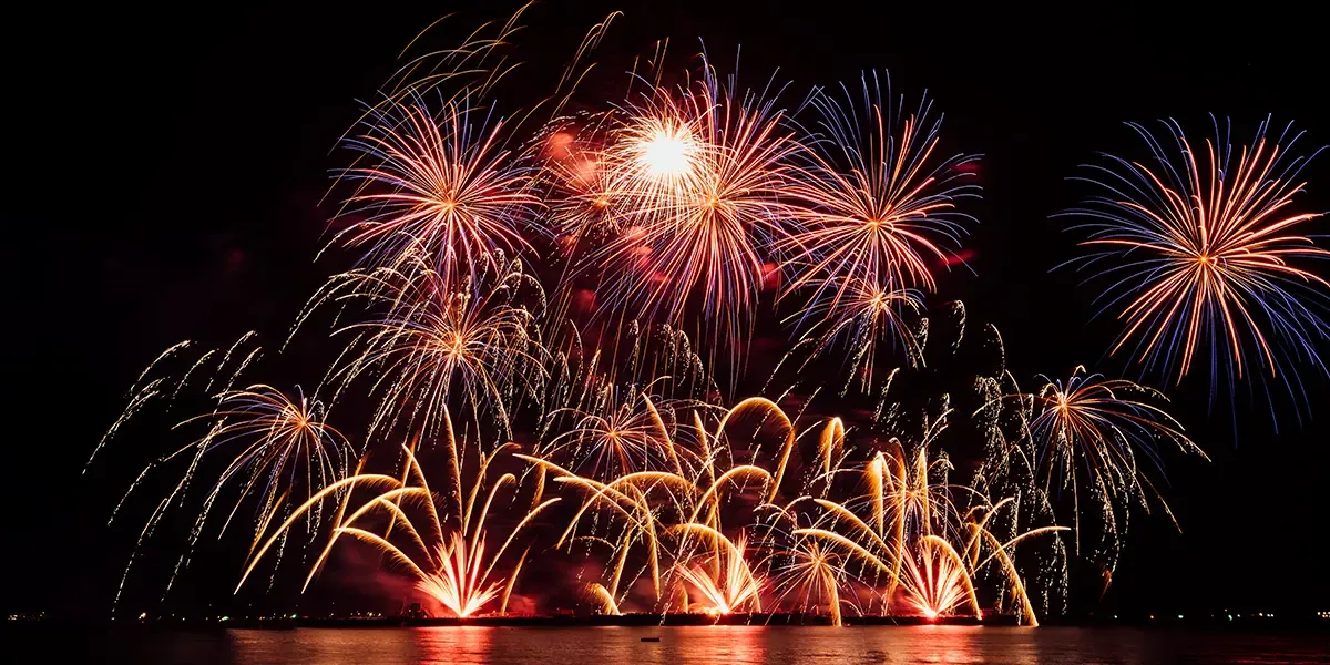 A Large Fireworks Display being set off over a bay at night